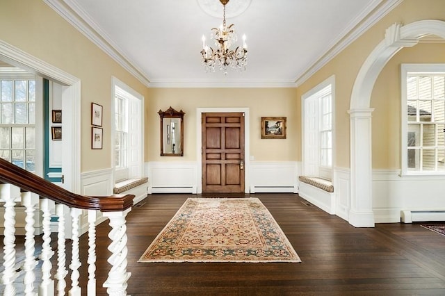 entrance foyer featuring a chandelier, baseboard heating, and a wainscoted wall