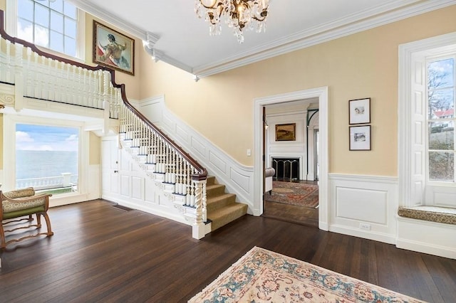 interior space featuring stairway, ornamental molding, a fireplace, and a chandelier