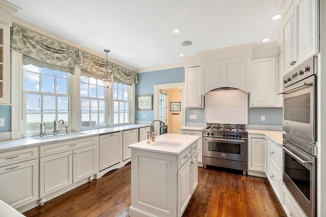 kitchen featuring a sink, appliances with stainless steel finishes, a kitchen island with sink, and light countertops