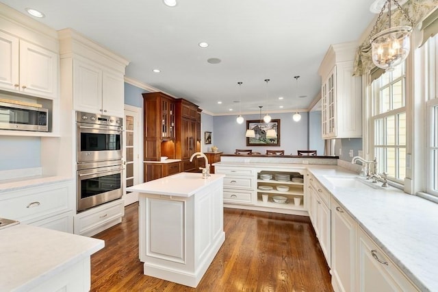 kitchen featuring a peninsula, glass insert cabinets, a sink, decorative light fixtures, and stainless steel appliances