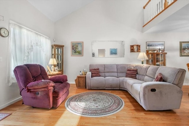 living area with high vaulted ceiling, wood finished floors, and baseboards