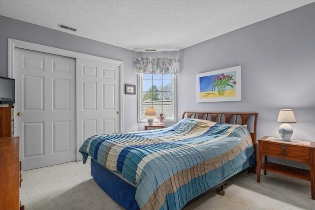 bedroom featuring visible vents, carpet floors, a textured ceiling, and a closet