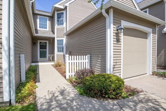 view of exterior entry with fence and an attached garage