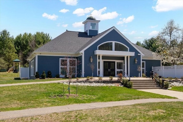 craftsman-style home featuring a shingled roof, a front yard, and french doors