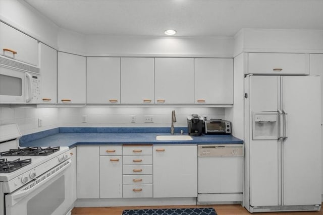 kitchen featuring white cabinets, white appliances, decorative backsplash, and a sink