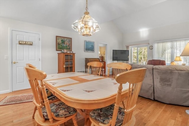 dining space with lofted ceiling, a chandelier, and light wood-type flooring
