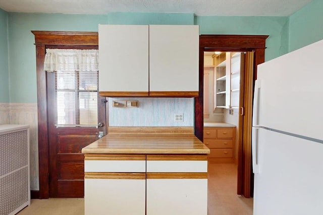 kitchen featuring white cabinetry, light countertops, wainscoting, freestanding refrigerator, and radiator heating unit