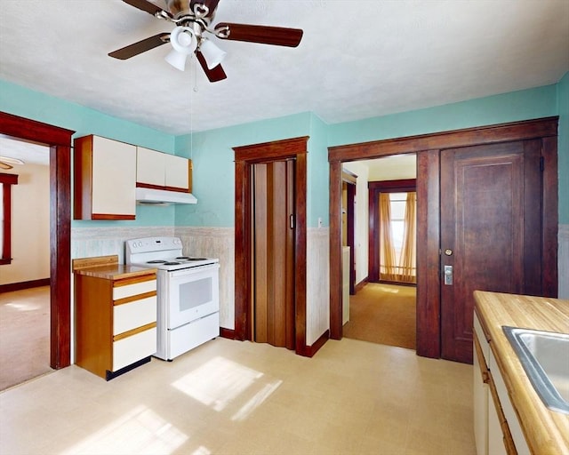 kitchen featuring white electric stove, light floors, white cabinets, a sink, and under cabinet range hood