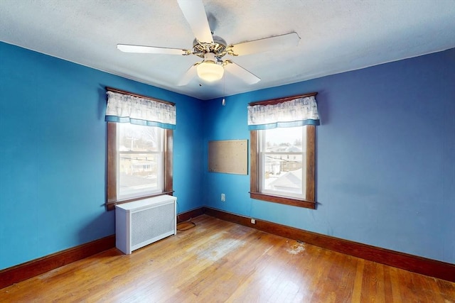 spare room with radiator heating unit, a wealth of natural light, and light wood-style floors