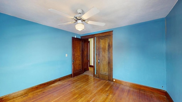 unfurnished room with ceiling fan, light wood finished floors, and baseboards