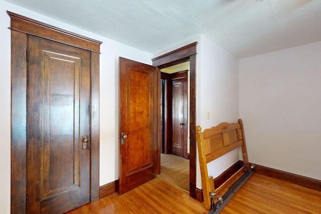 hall with baseboards and light wood finished floors