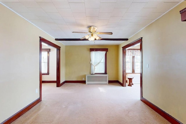 unfurnished room featuring radiator, light colored carpet, ceiling fan, and baseboards