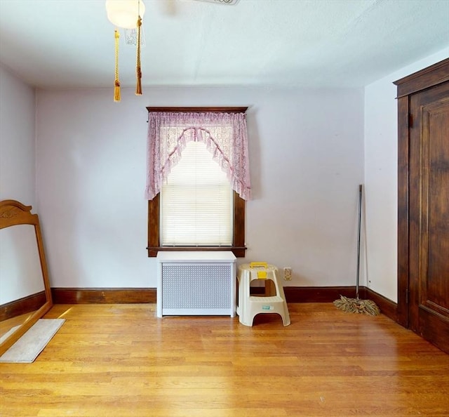 unfurnished bedroom with baseboards, light wood-style floors, and radiator