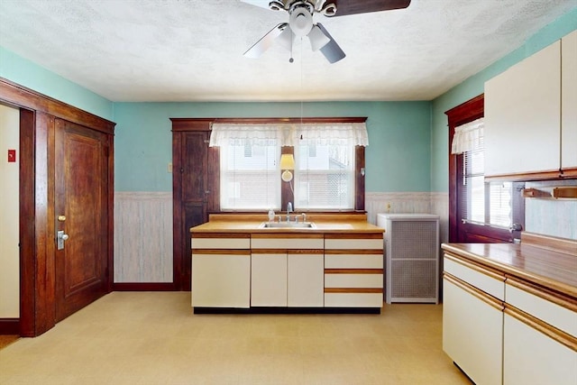 kitchen featuring wainscoting, light countertops, a sink, and a textured ceiling