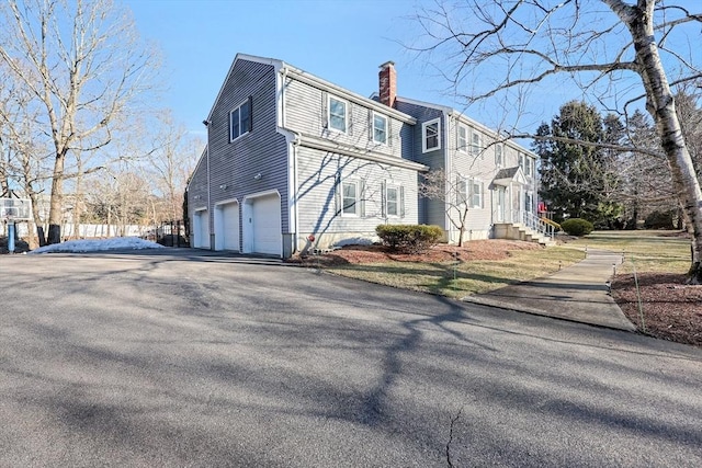 view of front of home featuring a garage, driveway, and a chimney