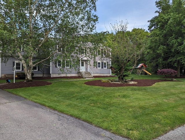 view of front of home with a front yard, a playground, and entry steps