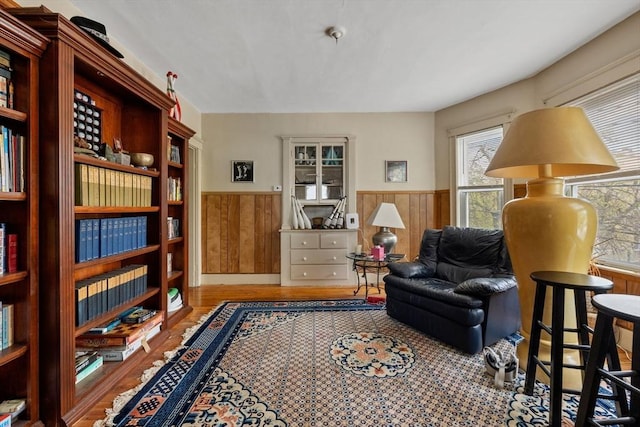 sitting room with wainscoting, wood walls, and wood finished floors
