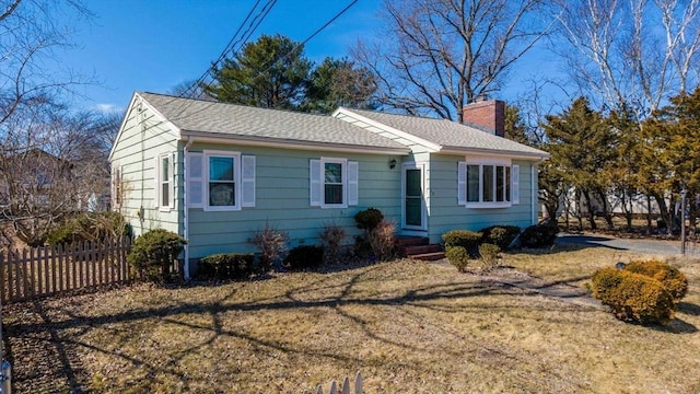 view of front of property featuring a shingled roof, a front yard, fence, and a chimney