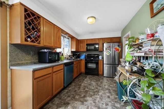 kitchen featuring backsplash, stone finish flooring, brown cabinets, black appliances, and a sink