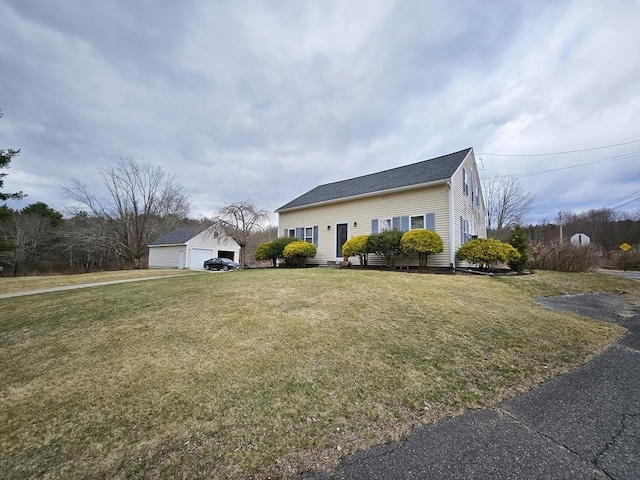 view of front of home featuring a front yard, a detached garage, and an outdoor structure