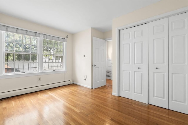 103 Claybourne Unit 103, Boston, MA 02124 - unfurnished bedroom with light wood-style flooring, baseboard heating, baseboards, and a closet