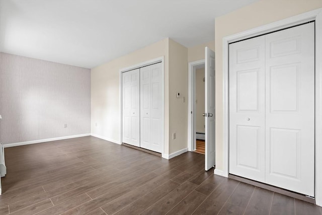 103 Claybourne Unit 103, Boston, MA 02124 - unfurnished bedroom featuring baseboards, dark wood-style floors, multiple closets, and a baseboard radiator