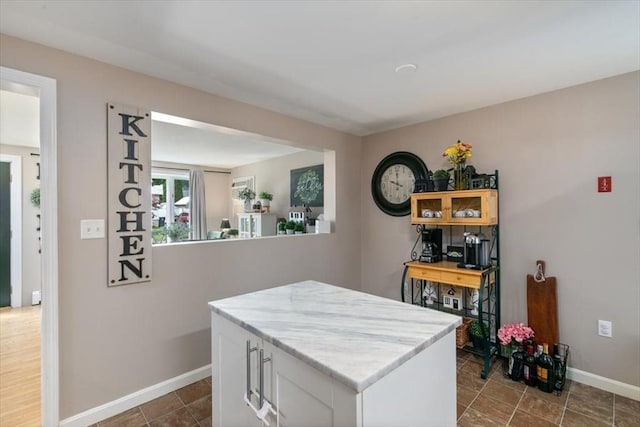30 Taylor St Unit 1, Haverhill, MA 01832 - kitchen with baseboards, white cabinetry, a kitchen island, and light stone counters