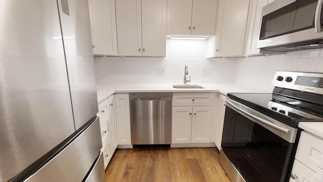 10 Williams Unit 39, Watertown, MA 02472 - kitchen featuring stainless steel appliances, a sink, light wood-style floors, tasteful backsplash, and light countertops