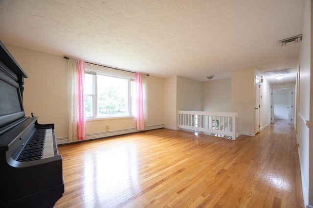 286 Mountain St, Sharon, MA 02067 - unfurnished living room featuring light wood-type flooring, a textured ceiling, and a baseboard radiator