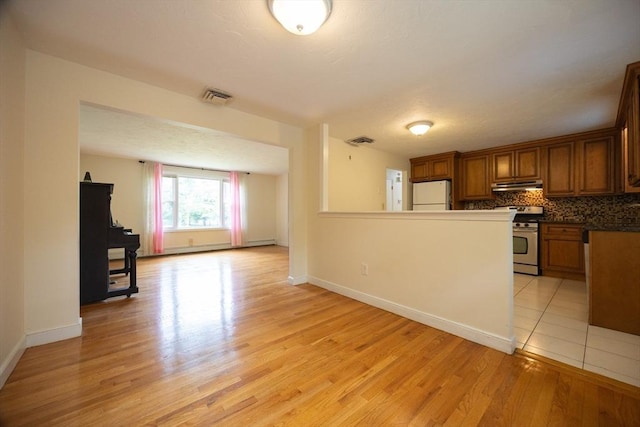 286 Mountain St, Sharon, MA 02067 - kitchen with freestanding refrigerator, stainless steel stove, under cabinet range hood, brown cabinets, and light wood finished floors
