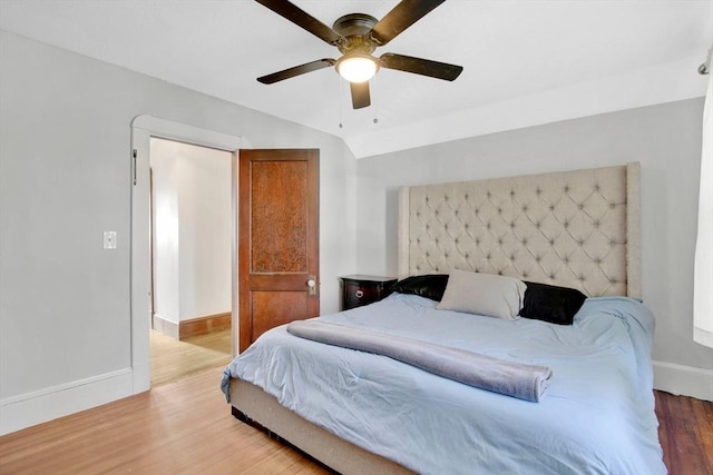 bedroom featuring light wood-style floors, vaulted ceiling, baseboards, and a ceiling fan