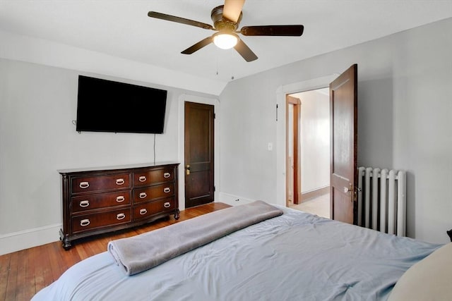 bedroom with a ceiling fan, baseboards, radiator heating unit, and wood finished floors