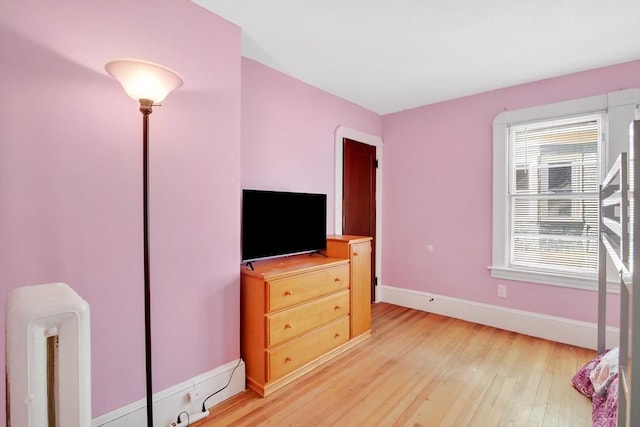 bedroom featuring light wood finished floors and baseboards