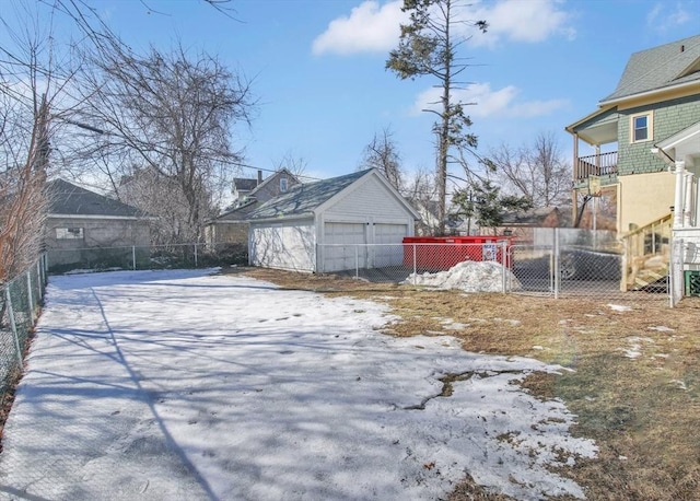 yard covered in snow with a garage, fence, and an outdoor structure