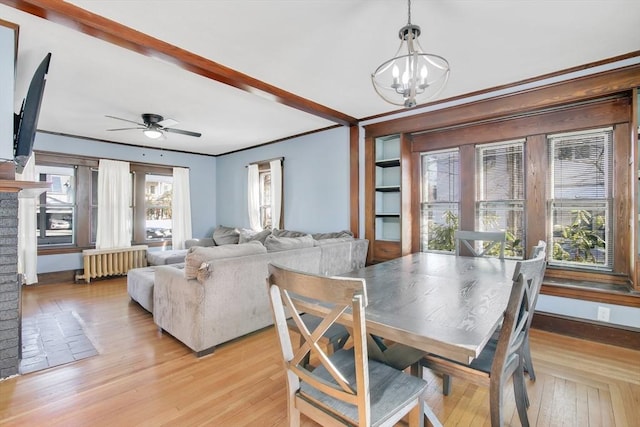 dining area featuring ceiling fan with notable chandelier, baseboards, ornamental molding, radiator, and light wood finished floors