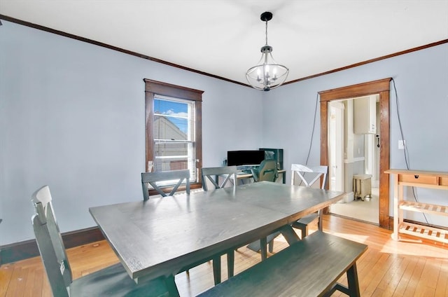 dining area with baseboards, ornamental molding, light wood-type flooring, and an inviting chandelier