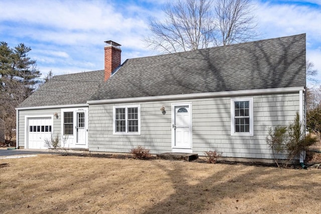 new england style home with a chimney, a shingled roof, a garage, and a front yard