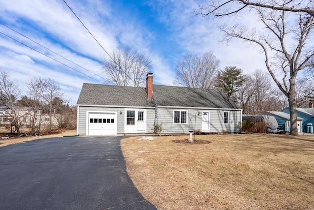 view of front of home with driveway, roof with shingles, a front yard, a garage, and a chimney