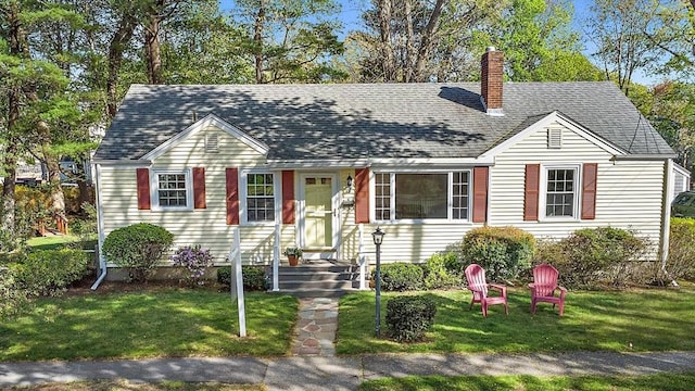 view of front facade with a chimney, a shingled roof, and a front lawn