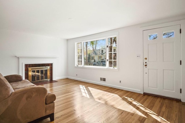 living room featuring wood finished floors, visible vents, baseboards, and a fireplace