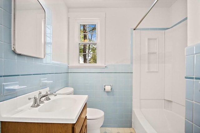 full bathroom with toilet,  shower combination, tile walls, wainscoting, and vanity