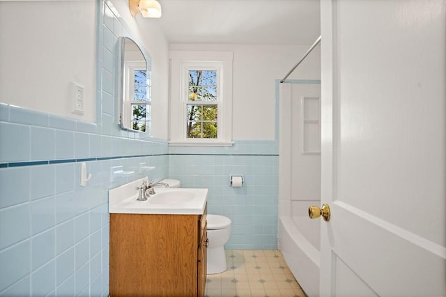 full bathroom with toilet, tile walls, wainscoting, vanity, and shower / bathing tub combination