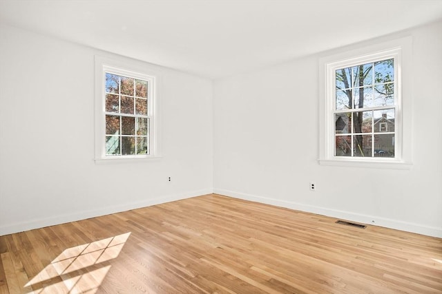 unfurnished room featuring visible vents, light wood-style flooring, and baseboards