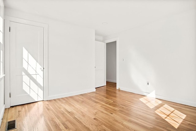 empty room with baseboards, light wood finished floors, and visible vents