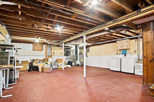 unfinished basement with washer and clothes dryer, gas water heater, electric panel, and heating unit