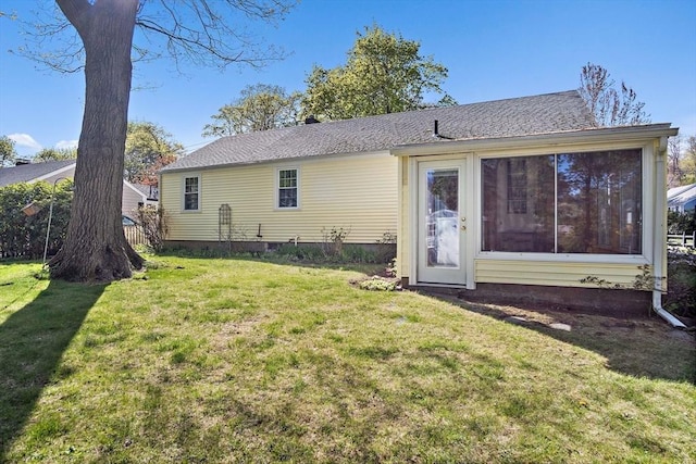 back of property with a lawn and roof with shingles
