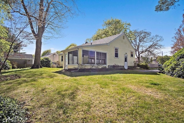 back of property featuring a lawn and a sunroom