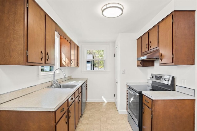 kitchen with stainless steel appliances, under cabinet range hood, baseboards, a sink, and light countertops