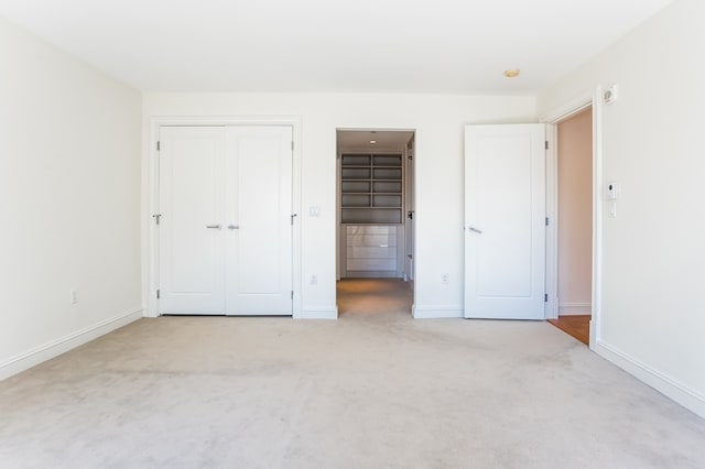 unfurnished bedroom with light colored carpet and a closet