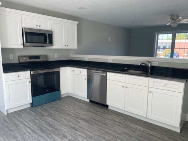 kitchen with stainless steel appliances, hardwood / wood-style floors, ceiling fan, and white cabinets